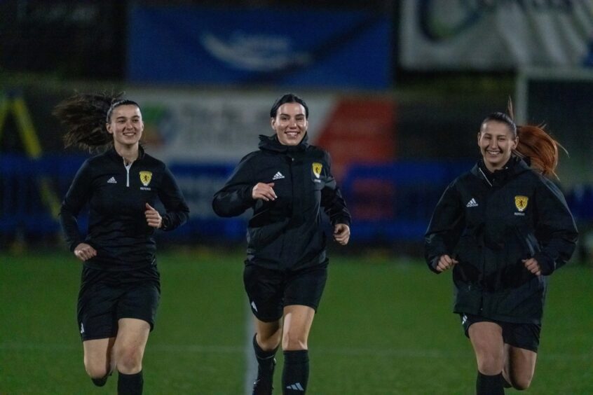 From left to right: Assistant referee Olivia Crawford, referee Abbie Hendry and assistant referee Paulina Ruszniak complete their warm-up by jogging.