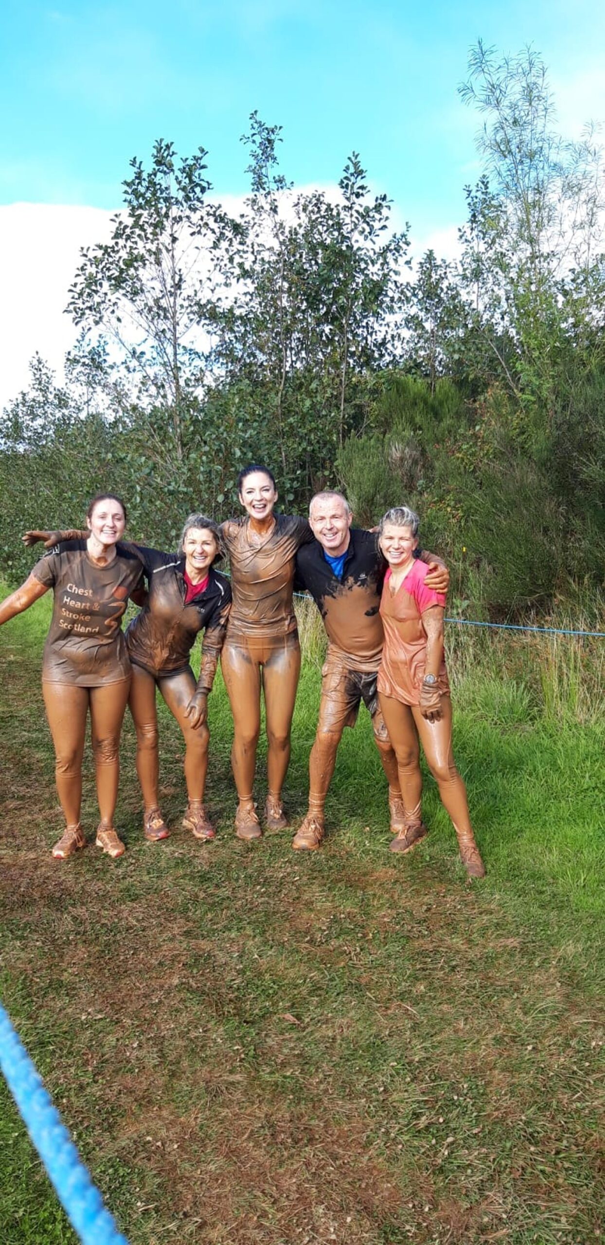 five very muddy runners pose for a picture after the Beast Race