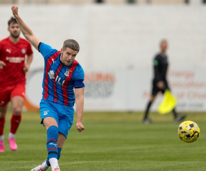 Inverness Caledonian Thistle midfielder Charlie Gilmour passes the ball with his right arm in the air for balance during a pre-season friendly at Brora Rangers on July 9, 2024.