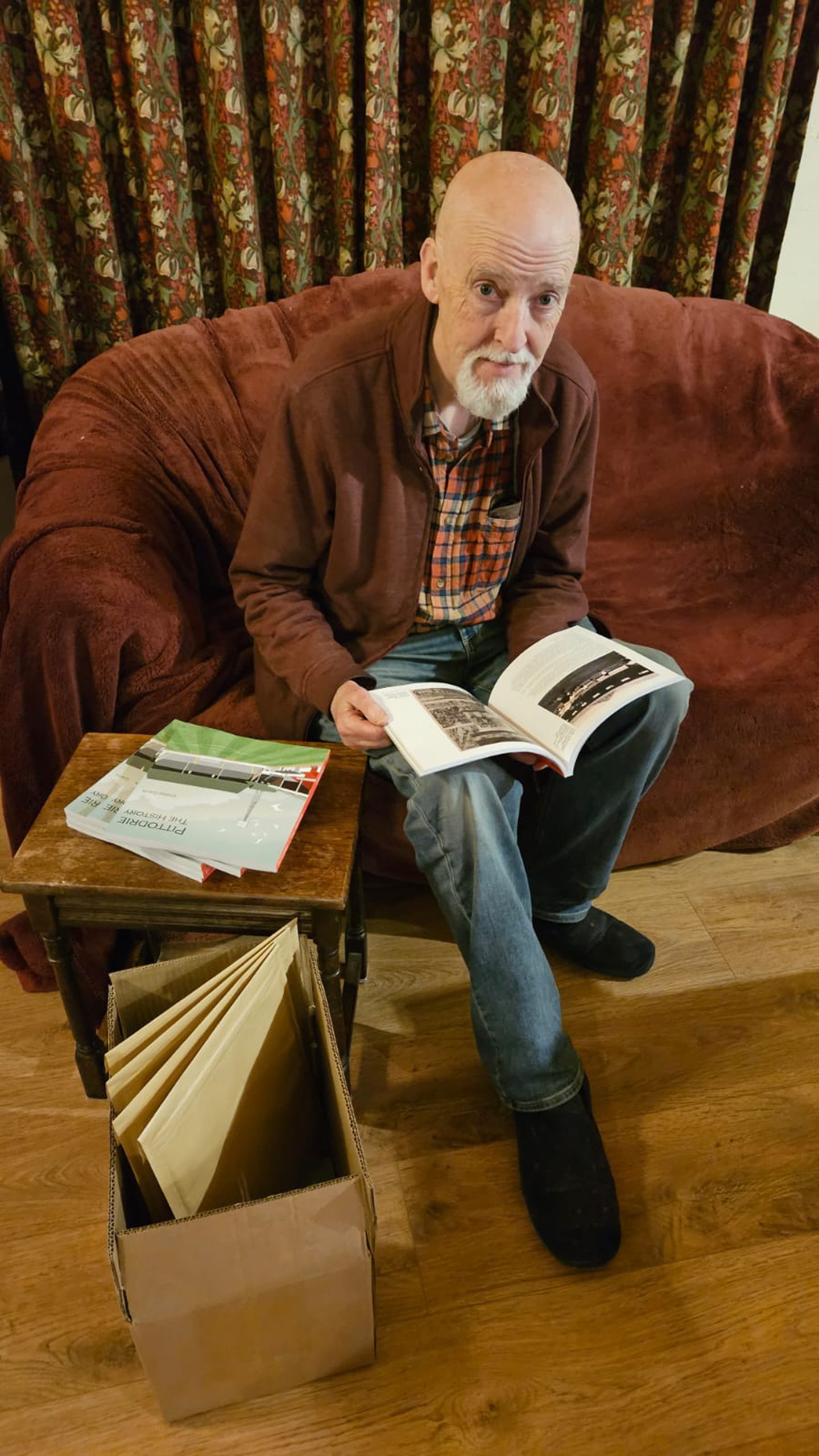 Aberdeen archivist Chris Gavin sits on a couch holding his new book