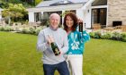 Rachael and Darren Reid, hold a bottle of champagne and key on the grounds of £3 million Surrey Home,