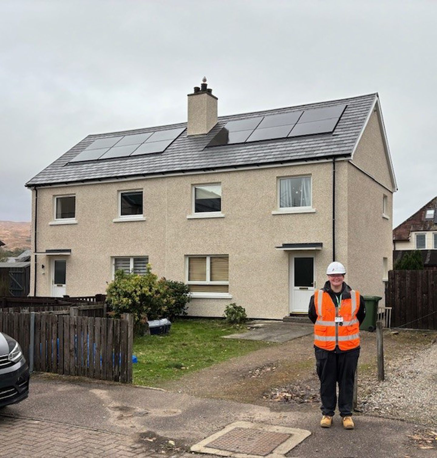 Diane Connolly-Phillip at work in a high viz jacket beside a house with solar panels 