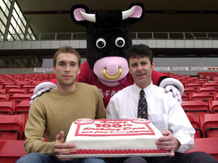 Russell Anderson, Steve Paterson and Angus the Bull with a cake given to the Dons to mark the club's 100th anniversary.