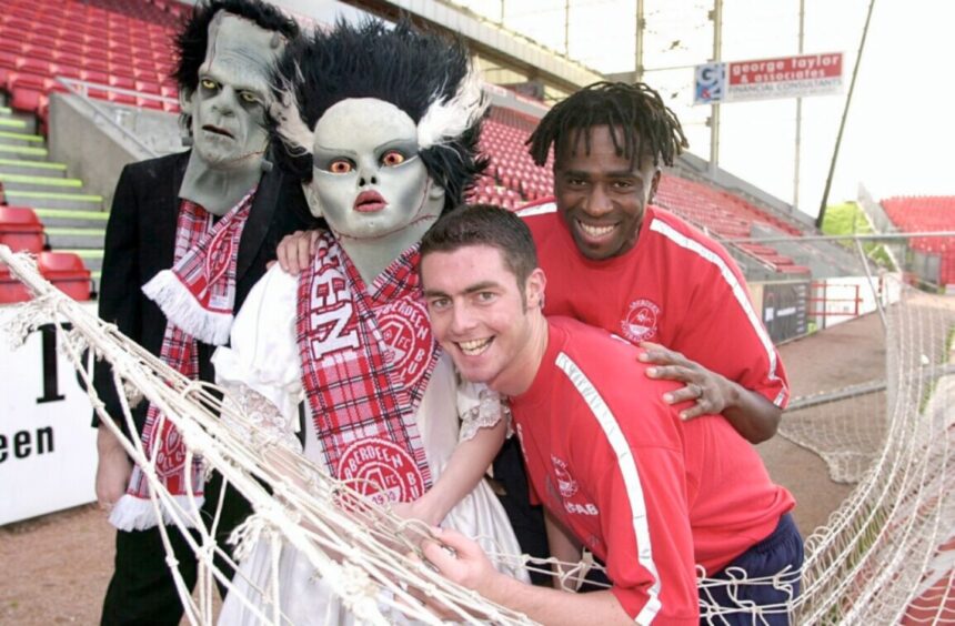 Frankenstein and his bride do their best to put the frighteners on Jamie McAllister and Eugene Dadi at Pittodrie ahead of a match against Hearts on 27 October 2001.