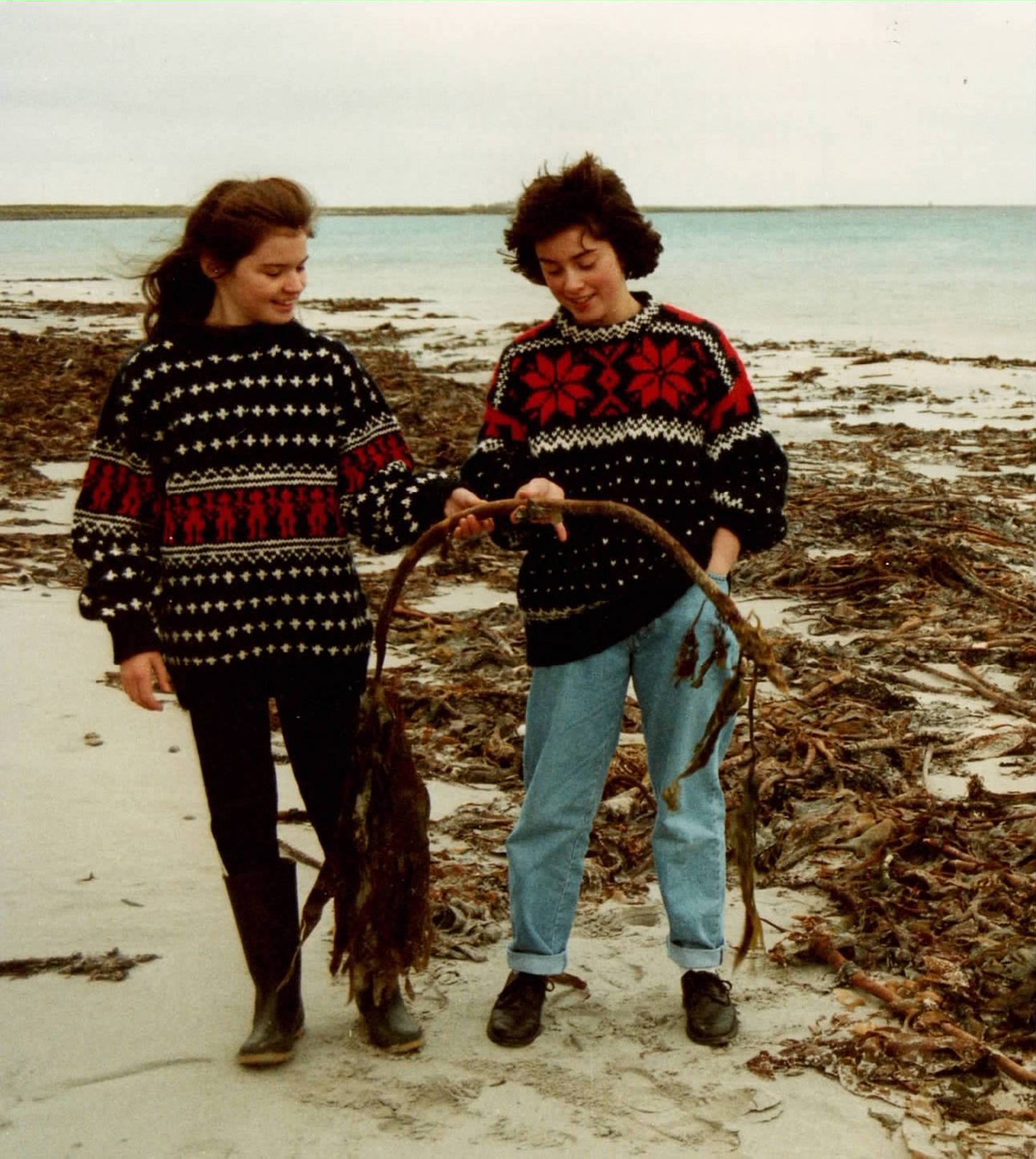 Young islanders modelling boldly patterned Isle of Sanday Knitters sweaters on the beach.