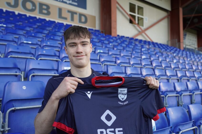 Ross County forward Calum Brown, 17, holds aloft a first-team jersey at the Global Energy Stadium after signing his first professional contract with the Scottish Premiership club on December 2, 2024. 