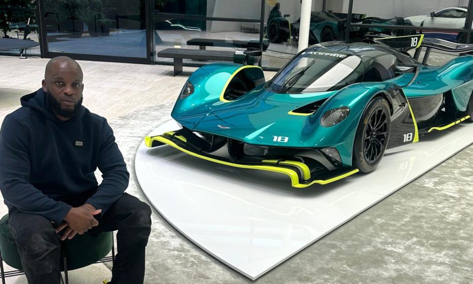 Former Aberdeen FC player Isaac Osbourne pictured next to one of Aston Martin's cars.