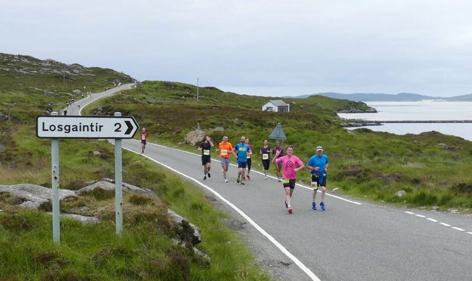 runners on a coastal road in the the Isle of Harris half marathon, with moor on one side and water on the other