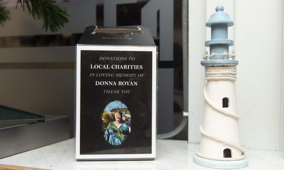 Donation box for Donna Royan next to ornament lighthouse. 