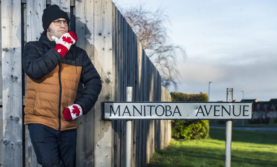 David Mackay leaning on fence next to Manitoba Avenue sign. 