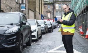 David Mackay standing on North Street in Elgin with notepad in hand.