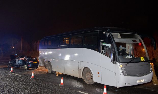 White bus with black car at the rear cordoned off by cones.