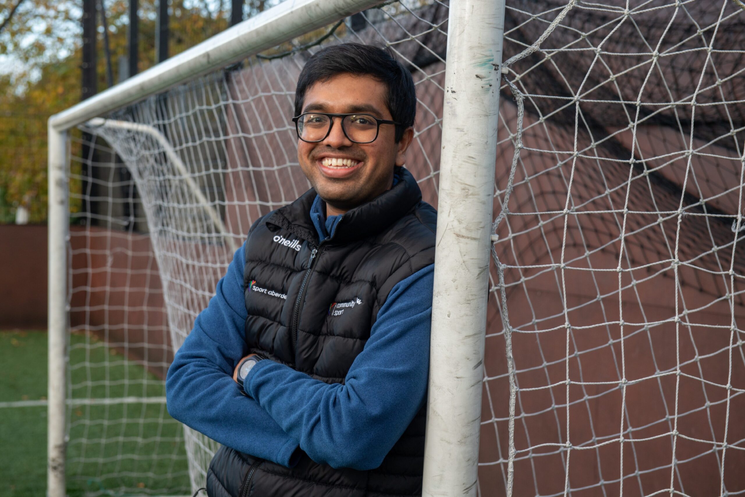 Rishabh Adhangale leaning on a football goal post at 5ives on Nelson Street. 