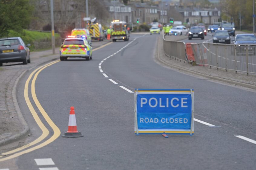 Road closed sign for a crash on the A96, with police vehicles on the road