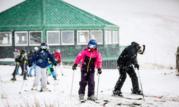 Skiers enjoying fresh snow at Glenshee with the Cairnwell Cafe behind them