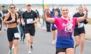 a joyful jogger at the Race for Life in Aberdeen raiser their hands and smiles