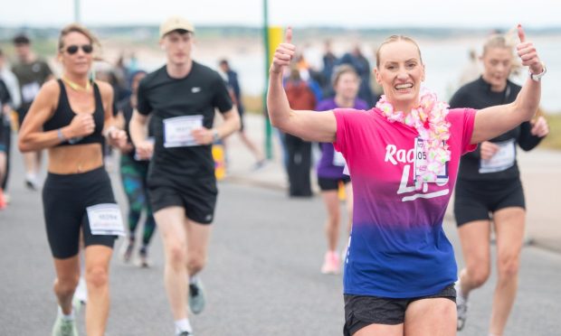 a joyful jogger at the Race for Life in Aberdeen raiser their hands and smiles