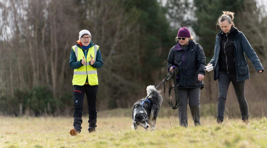 Megan walking in a field with dogs and their owners.