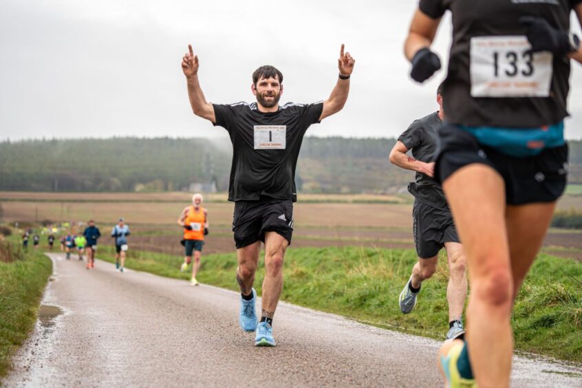 runners on a path through a field during the Moray Marathon. 