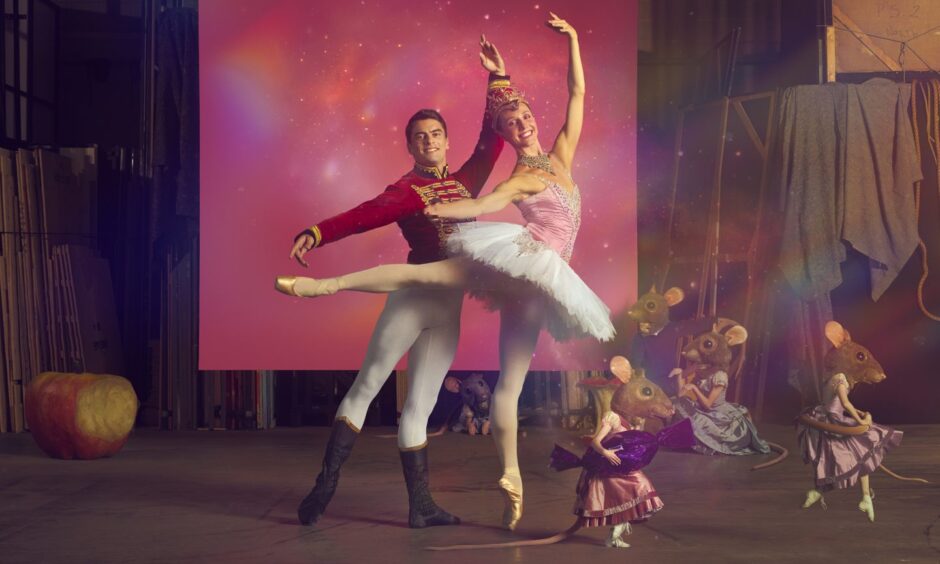 Male and female ballet dancers in front of pink background.