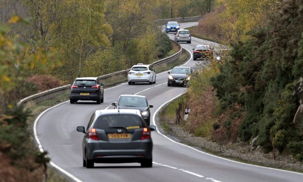 Traffic travelling in both directions on tree lined route.