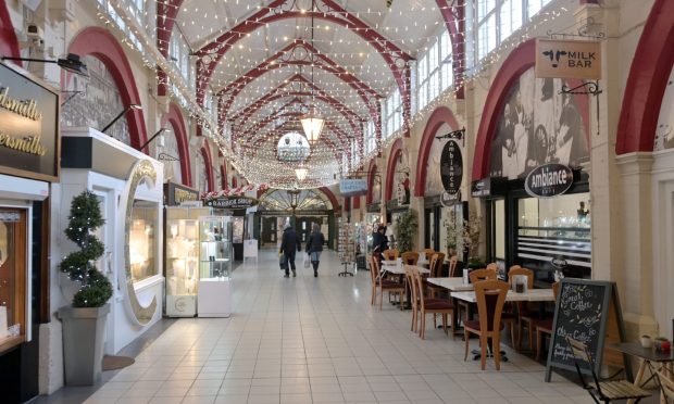 View of interioer of Inverness Victorian Market with red beams on the ceiling and shops on each side.