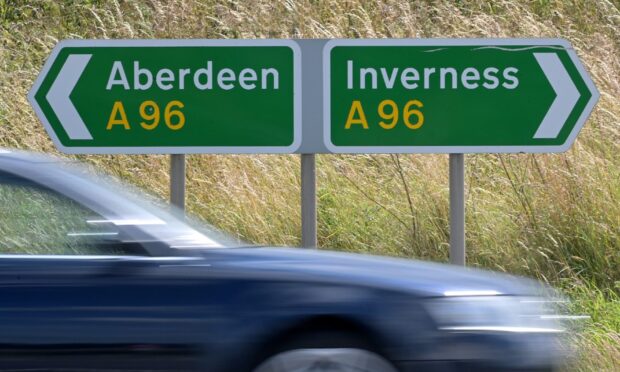 a car drives by road signs that are side by side. One reads Aberdeen A96 and the other reads Inverness A96