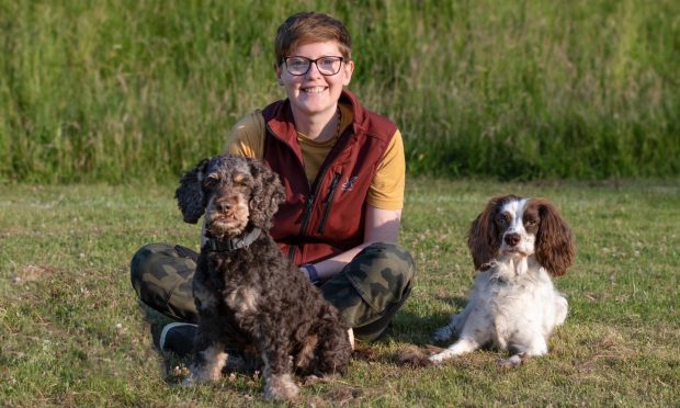 Megan Stuart-Bass sitting on the ground with her dogs Jaffa and Jacob.