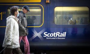 commuters walking past a ScotRail train at rail station.