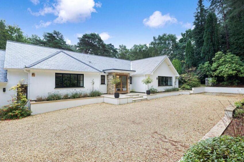 White facade of Surrey home with large gravel driveway and landscaping.