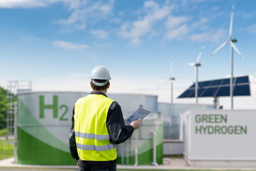 Engineer with tablet computer on a background of green hydrogen plant.