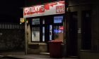 Facade of Chalky's Inverness newsagent with red sign light up in the dark