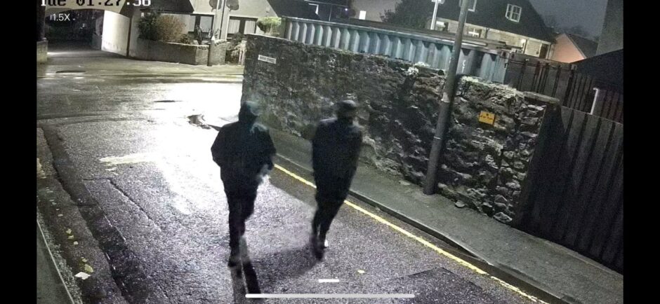 Two masked figures in black walking down an Inverness side street.