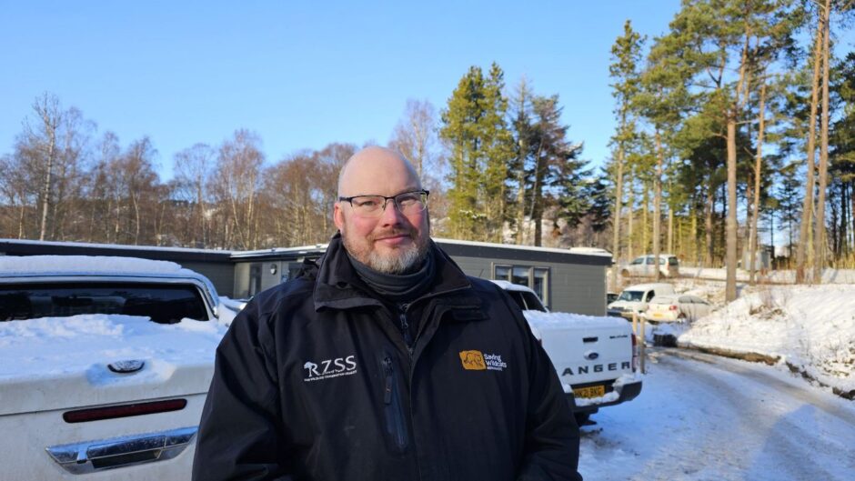 David Barclay, manager of the RZSS Saving Wildcats team at the Highland Wildlife Park, standing in front of buildings surrounded by snow.