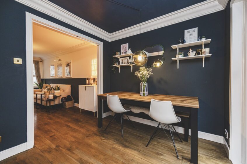 In the dining room the blue goes up to the ceiling, broken up by fresh light woodwork and deep coving.