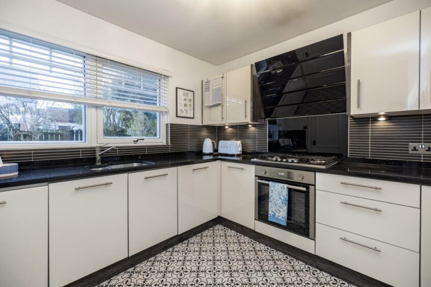 The kitchen is fitted with cream gloss units, black granite work surfaces and mosaic-effect flooring.