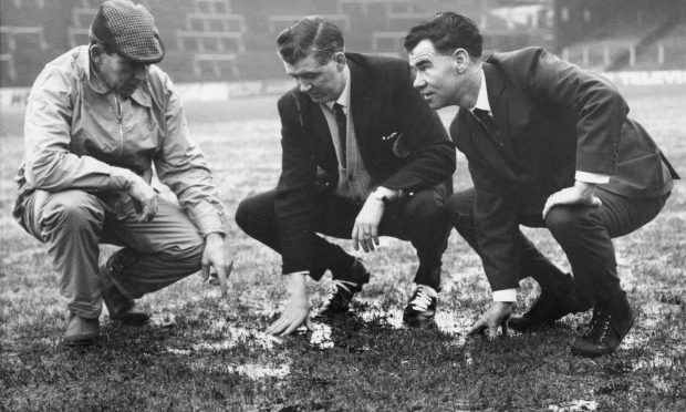 Referee Mr J. R. P. Gordon, of Tayport, who was to have taken charge of the Aberdeen-Elgin Scottish Cup-tie examines a waterlogged Pittodrie and decides there's no possibility of play. With him are Dons manager Eddie Turnbull (right) and one of his linesmen. Image: DC Thomson.