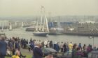 dozens of people watch as ships sail into a harbour as in the upcoming Tall Ships Races 2025