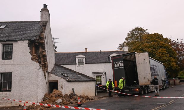 The scene in October last year. The damaged house is to the left, while emergency services can be spotted at the vehicle. The road is taped-off.