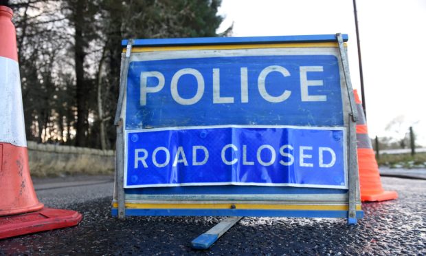 Blue police road closed sign alongside orange cones.