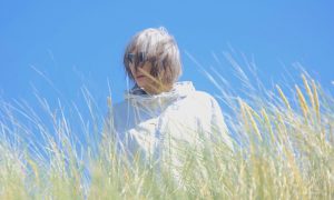 Aberdeenshire musician Fiona Soe Paing pictured in the countryside behind tall grass. Image by Isla Goldie