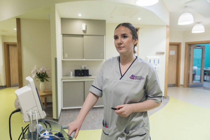 Student nurse in grey scrubs with a blood pressure monitor in the Highland Hospice Inverness 