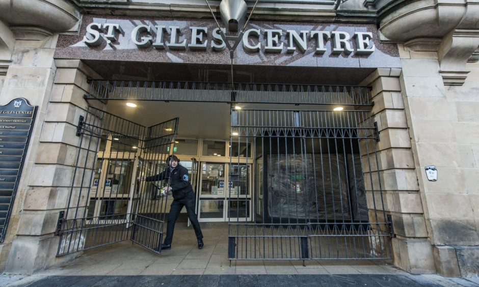 Security guard locking gates of St Giles Centre.