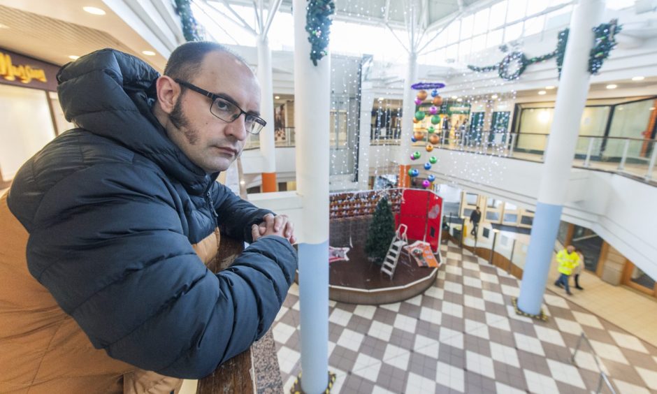 David Mackay leaning on railing in St Giles Centre. 