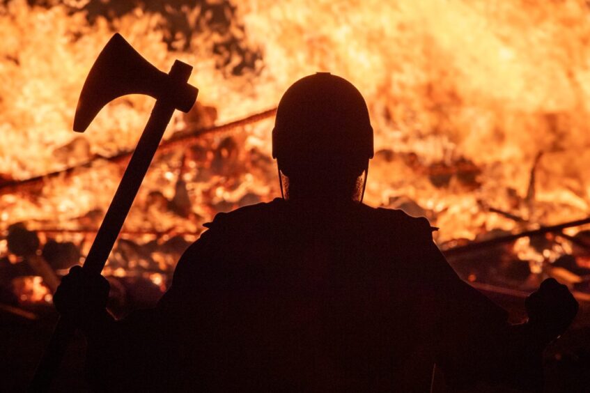 A silhouette of a man dressed as a Viking against a fiery backdrop at Up Helly Aa