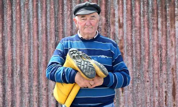 Mr Balgowan in a striped jumper and fisherman's cap, holding a pair of yellow welly boots, that must have been much-used on board.