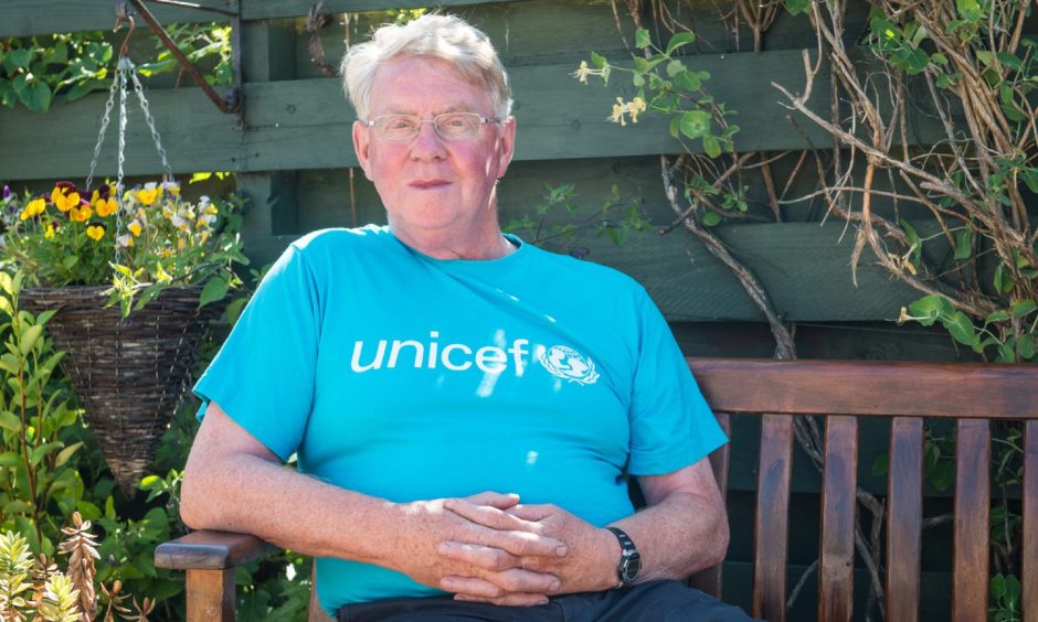 Bill Hope sitting in chair in Unicef t-shirt. 