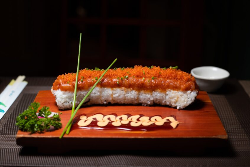 Sushi dish on a wooden board with chopsticks. 