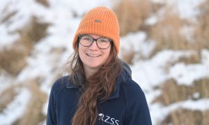 Dr Helen Senn, Head of Conservation at the Highland Wildlife Park wearing a blue zipper fleece and an orange hat.