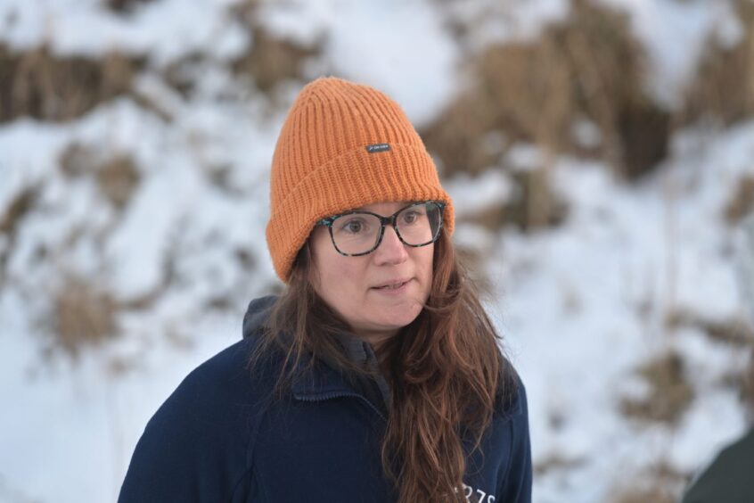 Dr Helen Senn, Head of Conservation at the Highland Wildlife Park wearing a blue zipper fleece and an orange hat.